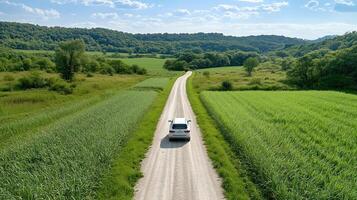 car driving on dirt road through lush green fields and hills photo