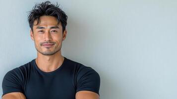 Confident Asian man smiling in black shirt against light background photo