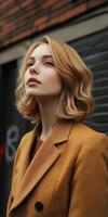 Young woman with stylish hair and coat looking upwards in urban setting photo