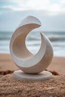 Elegant stone sculpture on sandy beach with ocean backdrop at sunset photo