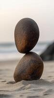 Balanced stones create striking natural sculpture on sandy beach at sunset photo