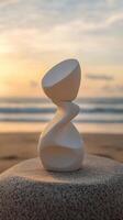 Elegant white sculpture stands on a beach at sunset by the ocean photo