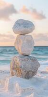 Balancing stones on a serene beach at sunset near the ocean photo