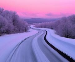 Winding road through snowy landscape at dawn with pink sky photo