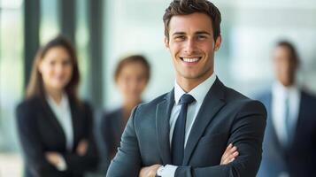 Confident young businessman in smart suit standing with arms folded in modern office environment photo
