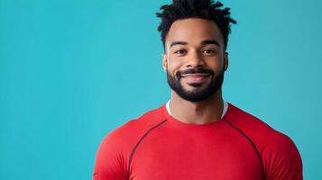 Cheerful and confident young African man with beard and afro hairstyle wearing a red shirt,smiling directly at the against a vibrant turquoise colored background. photo
