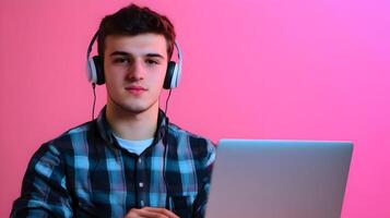 Concentrated Young Male Student Engaged in Academic Research With Laptop and Headphones on Vibrant Color Background,Representing the Focused Mindset of a Modern Scholar Immersed in Digital Learning photo