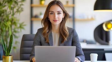 Portrait of a Stylish Caucasian Female Manager Sitting at a Desk and Using a Laptop Computer in a Contemporary Office Setting of a Marketing Agency. photo