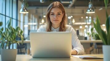 Stylish and Confident Caucasian Female Manager Sitting at a Desk,Using Laptop Computer in a Modern,Well-Lit Office Environment of a Marketing Agency or Corporate Workspace photo