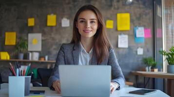 Portrait of a Confident Young Caucasian Female Manager Sitting at a Desk and Using a Laptop Computer in a Contemporary Marketing Agency Office Setting photo