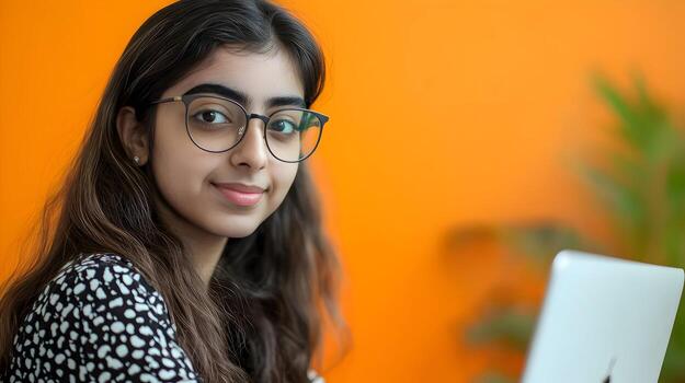 retrato de un joven, seguro de sí mismo hembra vistiendo lentes y utilizando un ordenador portátil computadora en un moderno oficina medio ambiente, sugiriendo su papel como un eso especialista,software ingeniero,o desarrollador. foto