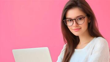 Confident Young Female Software Engineer or Developer Working on Laptop Computer in Modern Office or Studio Environment with Pink Background photo