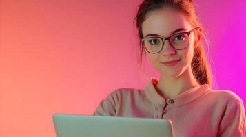 Confident and Focused Young Woman Wearing Glasses Using Laptop Computer in Vibrant Pink and Purple Studio Setting,Representing IT Specialist,Software Developer or Engineer photo