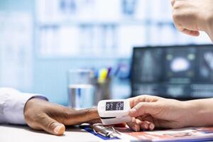 Skilled doctor taking the oxygen saturation measurement to check vital signs and parameters, healthcare industry. Medical specialist using an oximeter for check up consultation. Close up. photo
