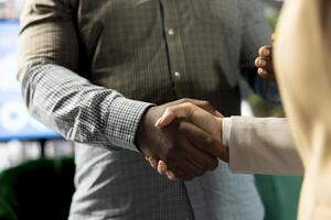 Interviewer holding meeting with job candidate, doing greeting handshake, asking questions and presenting company background. Close up of human resources worker interviewing man for open position photo
