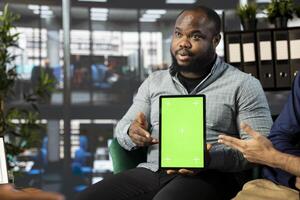 Startup CEO attends meeting to talk about new business vision with executive board member, using chroma key tablet. African american man using mockup device to pitch investment strategy to manager photo