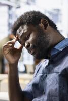 Exhausted employee rubbing forehead while analyzing datasets on computer, checking accounting figures. Tired worker suffering headache from overworking, solving tasks for team project photo