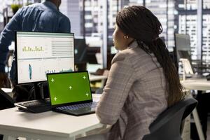 Woman at her desk working on data analysis next to mockup display, engaged in business tasks and budget management to drive effective corporate strategy. Analyst reads reports numbers. photo