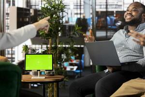 Isolated screen tablet next to smiling employee chatting with coworker during business meeting. Mockup device next to jolly worker having fun with colleague while doing research analysis photo