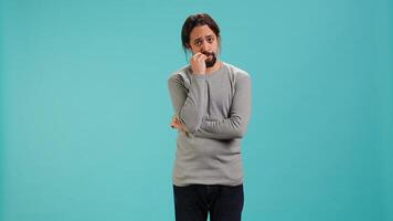 Distraught man biting nails, being afraid of receiving troubling bad news, studio background. Anxious person suffering from mental health problems, having negative emotions, camera A photo