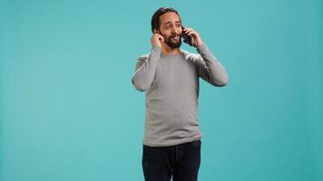 Joyous man with positive emotion enjoying talking with friends in phone call using smartphone, studio background. Happy person with smile on face, receiving good news during telephone call, camera A photo