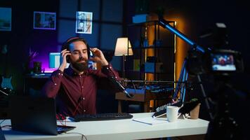 Tech expert testing headphones, mouse and keyboard, reviewing them for online streaming platforms. Internet show host presenting audio device and computer peripherals, camera B photo