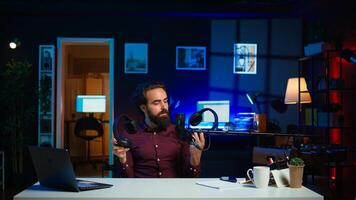 Tech expert testing headphones, review them for online streaming platforms. Professional audiophile hosts internet show, using sound mixer to check audio device sound sensitivity, camera B photo