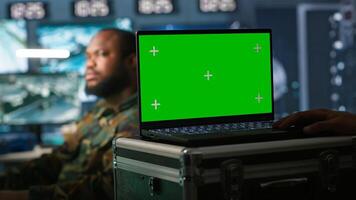 Soldier using tracking software on green screen laptop to gain info against enemies. Army expert using chroma key notebook to gain intel helping troops, coordinating mission activities, camera A photo