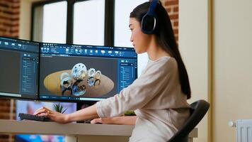 Asian industrial designer puts headset on and works with 3D rendering software, creative freelance tasks. Using dual monitors to enhance multitasking and efficiency for design projects. Camera B. photo