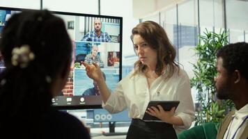 Employees attending an online remote videocall meeting with general manager, presenting project updates for efficiency. Work team ensuring strategic goals achievement in a boardroom. Camera B. photo
