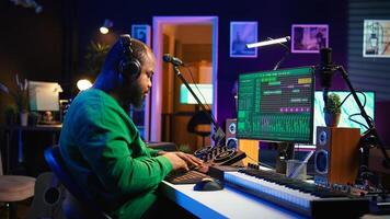 Confident music engineer working on mixing console in home studio, producing new sounds for a song and editing volume levels in daw software. Audio technician recording acoustic files. Camera B. photo