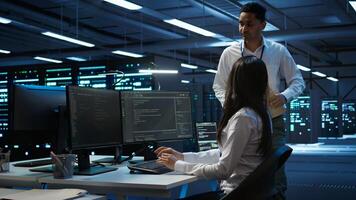 Management executive in data center ensuring system can handle networking tasks. Coworkers doing brainstorming in server room, tracking network traffic with PC, making improvements, camera B photo