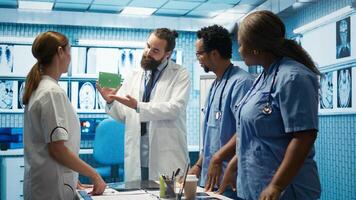 Medic presenting a box with isolated mockup screen during a meeting for disease prevention, conducting analytics and control of x ray scans results in a facility. Radiology department. Camera B. photo