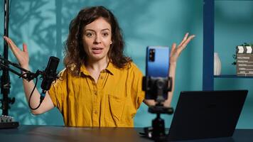 Streamer doing live broadcast on smartphone on holder, talking to audience about recent news headlines. Media star talking with viewers, presenting facts in entertaining manner, camera A photo