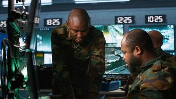 Military agents in war room look at intel folder files on enemy battle formation. Intelligence agency professionals read mission case file to collect data on opponents strategy, camera A photo
