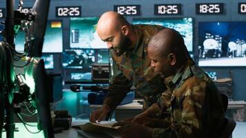 Team of military officers in command center look at intel folder files on enemy battle formation. Intelligence corps colleagues read mission case file to collect data on opponents strategy, camera A photo