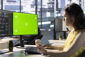 Developer using mockup PC, fixing applications issues, dealing with databases and server configuration. IT expert using green screen computer, optimizing company software for improved performance photo