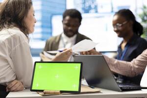 Employees and shareholders using chroma key screen in a corporate briefing, reviewing economic indicators on papers. Business people discussing finance planning and setting strategic goals. photo