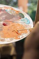 Confident painter mixing different watercolors on a palette to create the perfect dye shade and apply on canvas, working on fine art. Artist uses vibrant colors and dynamic brushwork. Close up. photo