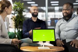 Green screen tablet next to multiethnic team of office clerks implementing business strategies to improve operational profitability. Mockup device next to bookkeepers setting revenue goals photo