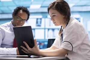 Healthcare provider presenting lab test results to a patient in cabinet, reviewing x ray and MRI scans to assist man on the road to recovery. Medical technology in diagnostics and care management. photo