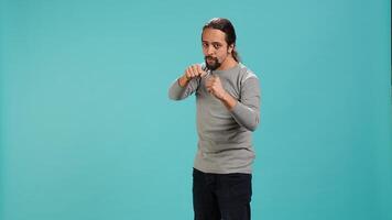 Man pretending to fight, throwing punches, holding defensive guard. Martial artist person doing mock boxing, holding combat stance, exercising, isolated over studio background, camera A photo
