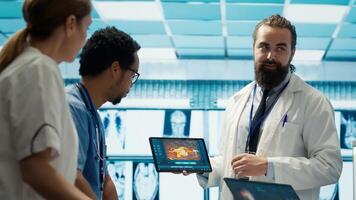 Neurology specialist examines magnetic resonance imaging brain scan with team during a meeting, looking at tomography for accurate neuroscience diagnosis. Diverse team of doctors. Camera A. photo