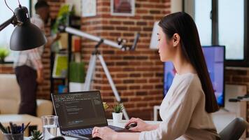 Asian freelancer woman works on programming code in a modern office at home, using her laptop for computer science. IT specialist supports coding, web development and digital innovation. Camera B. photo