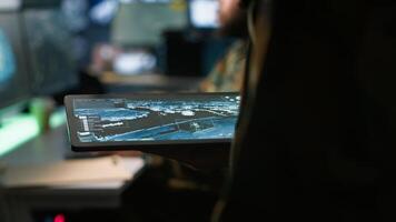 Army operative using tablet in command center housing operational missile defense system designed to intercept ballistic rockets. Close up of expert using tracking software on device, camera A photo