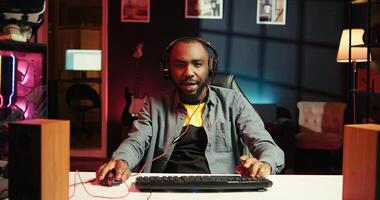 Man having fun playing videogames on PC, putting on headset to chat with teammates. Gamer battling rival players online, communicating with friends through headphones, camera B photo