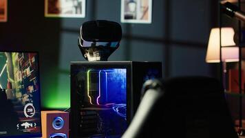 RGB lit parts on opened gaming PC tower next to keyboard, stereo speakers, display and high tech VR headset in empty apartment. Computer with modern hardware, monitor and virtual reality glasses photo