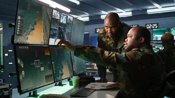 Air force officer and colleague performing tactical level surveillance in command post. Team of military specialists doing brainstorming, using radar equipment to look at assault zones, camera B photo