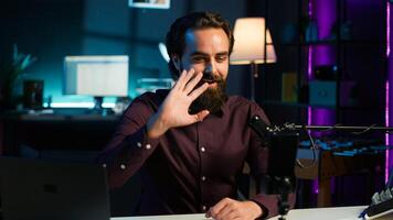 Content creator adjusting professional microphone in studio before starting vlog, recording with selfie camera. Man in neon lit home studio preparing equipment, filming with smartphone, camera A photo