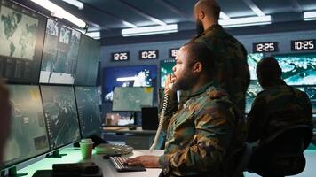 Military officer making telephone call to relay enemy info gained using tracking equipment. Army specialist talking on phone, giving intel helping troops, coordinating mission activities, camera B photo